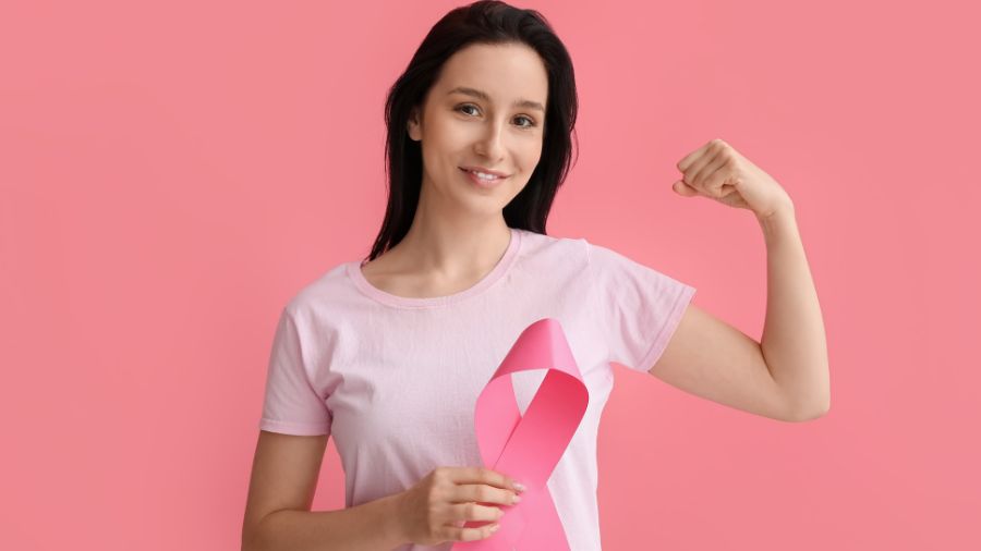 Meme kanseri farkındalığını temsil eden pembe tişörtlü, pembe kurdele tutan ve kol kasını gösteren kadın