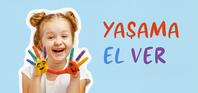 Gülümseyen bir kız çocuğu, elleri renkli parmak boyalarıyla kaplı, beyaz kumaş üzerine el izini bırakıyor. LÖSEV’in “Yaşama El Ver” projesi için umut ve dayanışmayı simgeliyor.